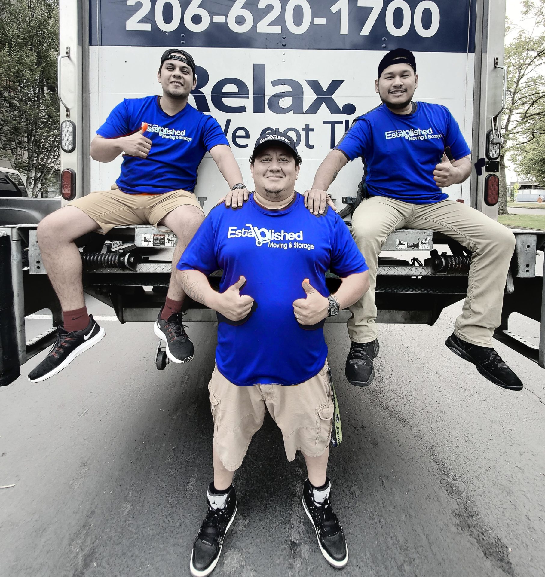 established moving & storage employees give a thumbs up behind their truck