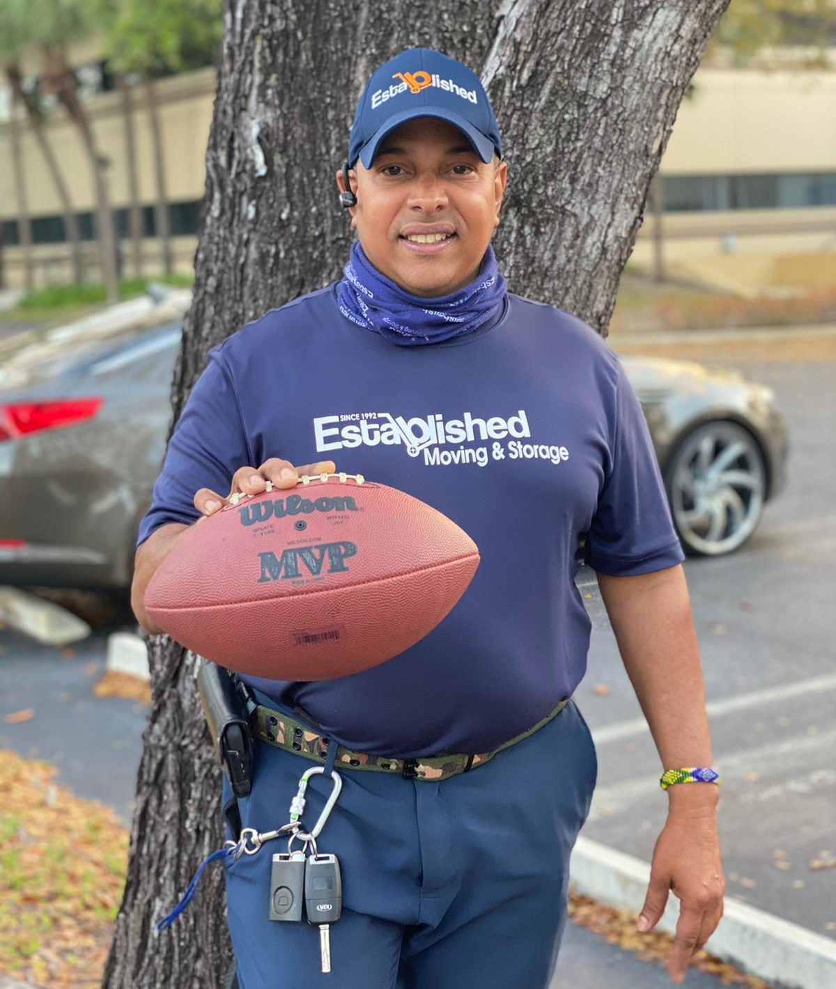 an established moving & storage employee holds up a football