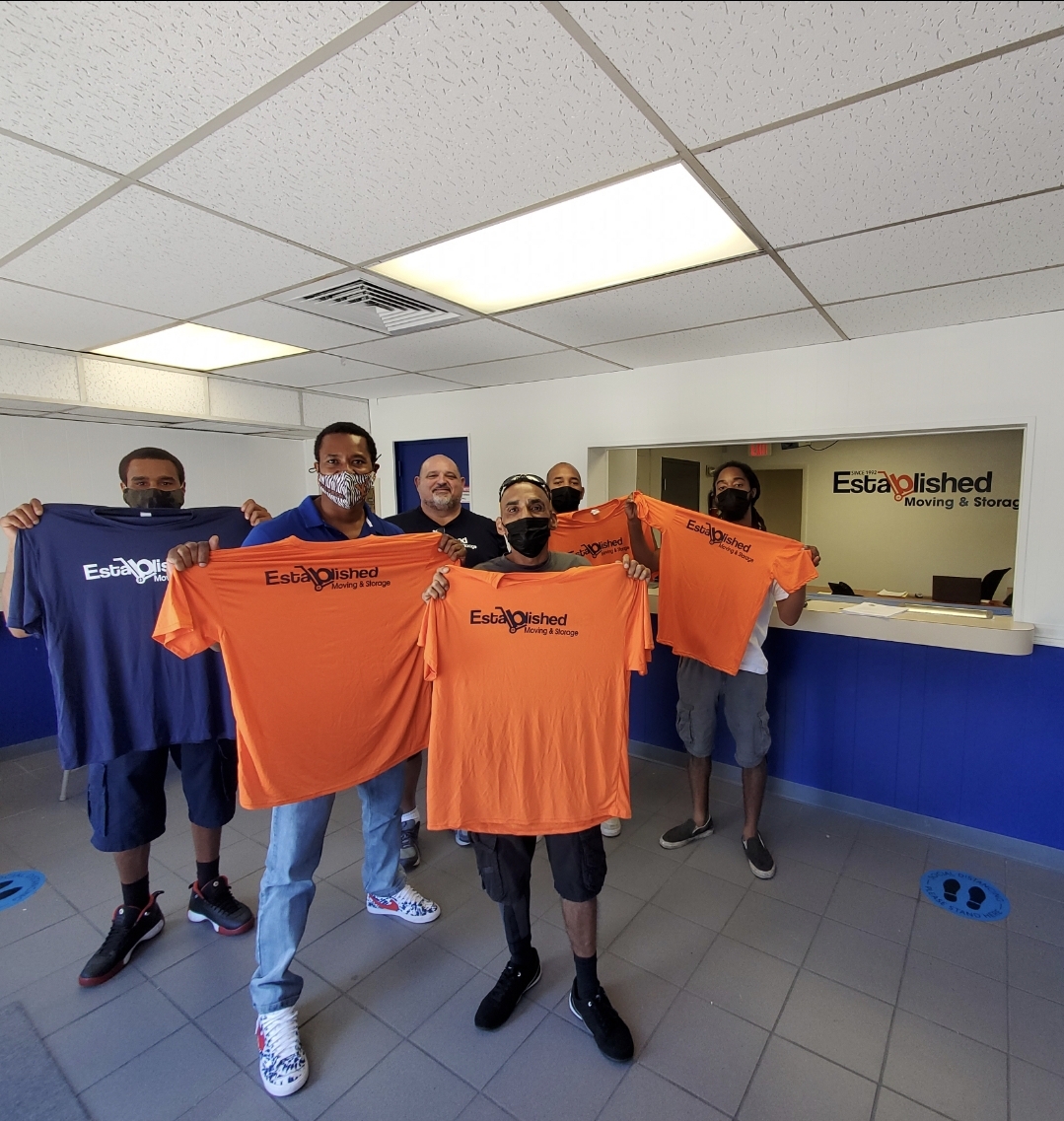 new members of the established moving & storage team poses with new team shirts