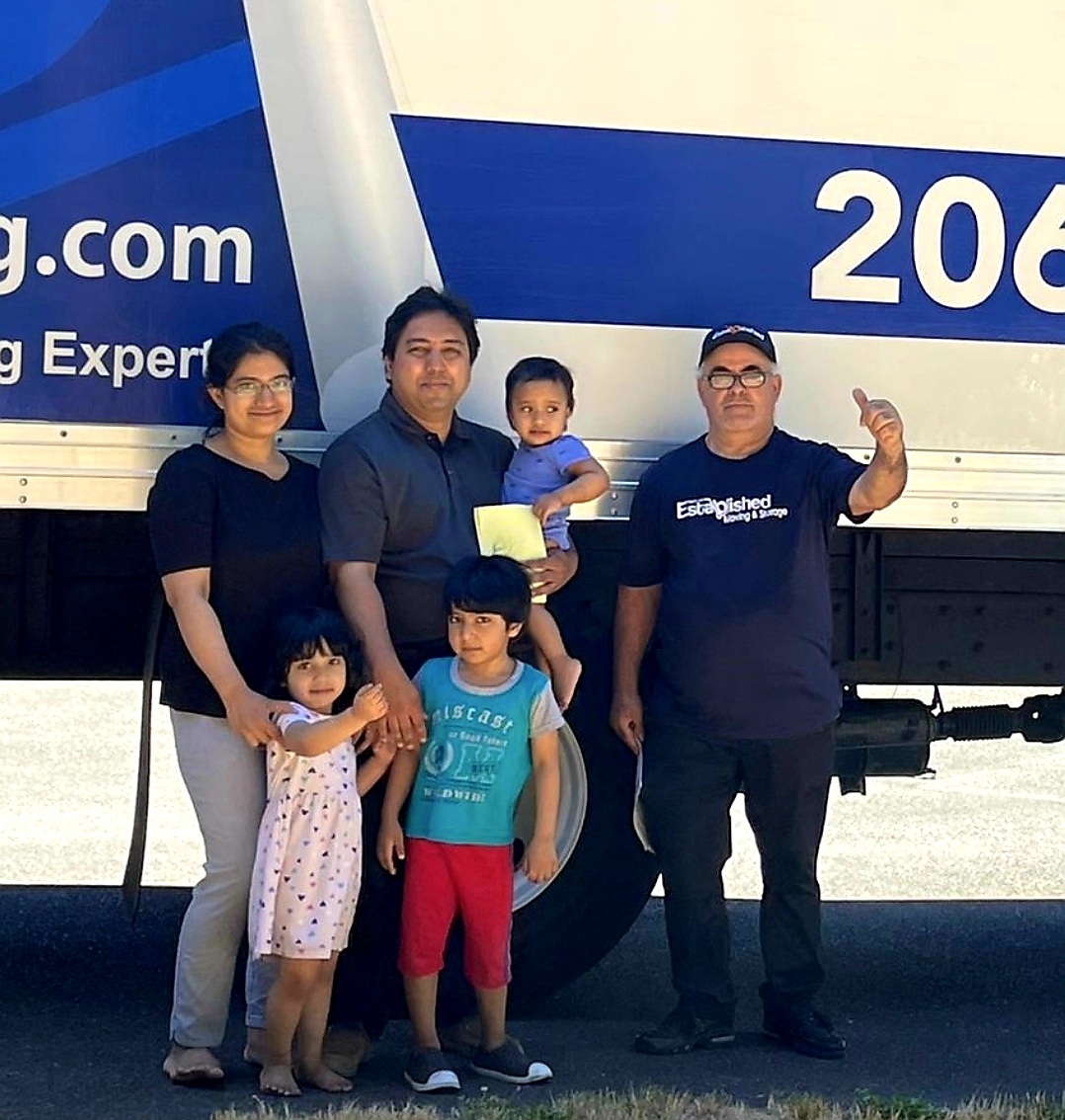 a family poses in front of the established moving & storage moving truck