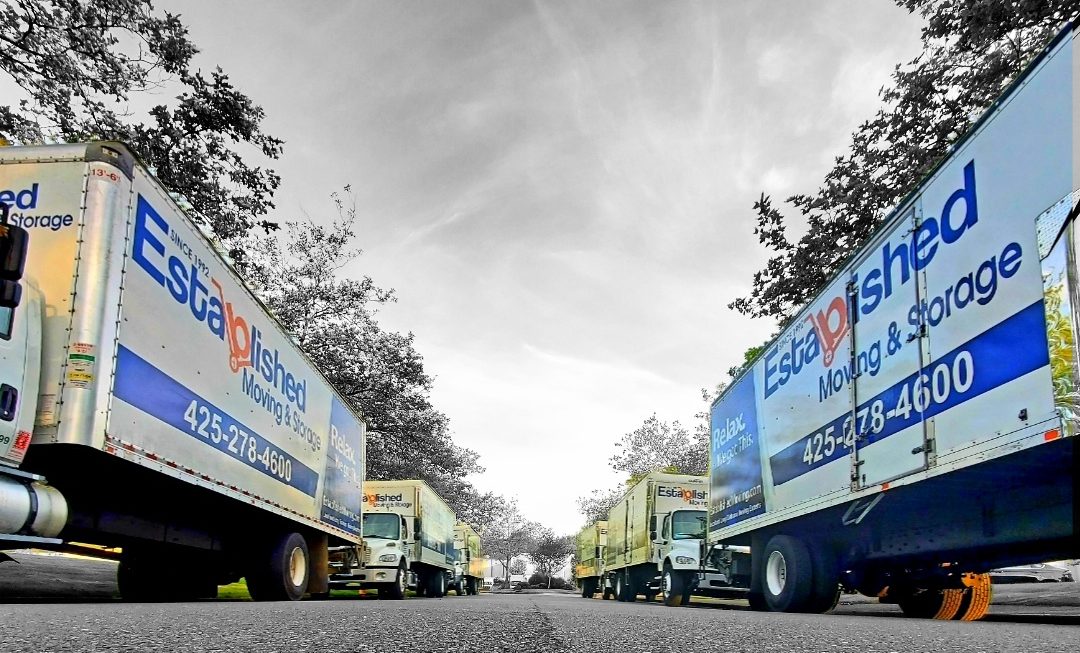 established moving & storage trucks line the sides of a street
