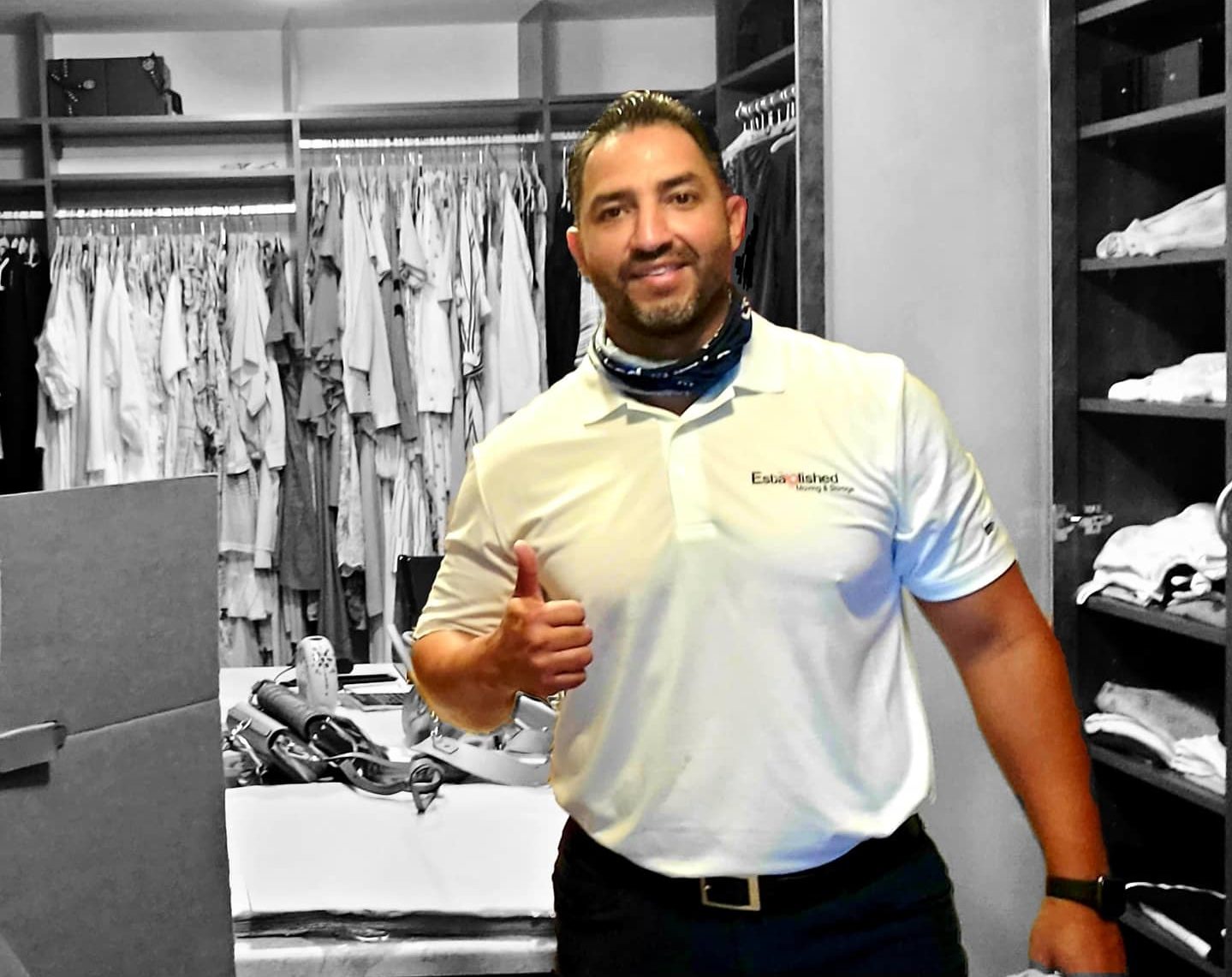 a manager at established moving & storage gives a thumbs up in a closet he's packing