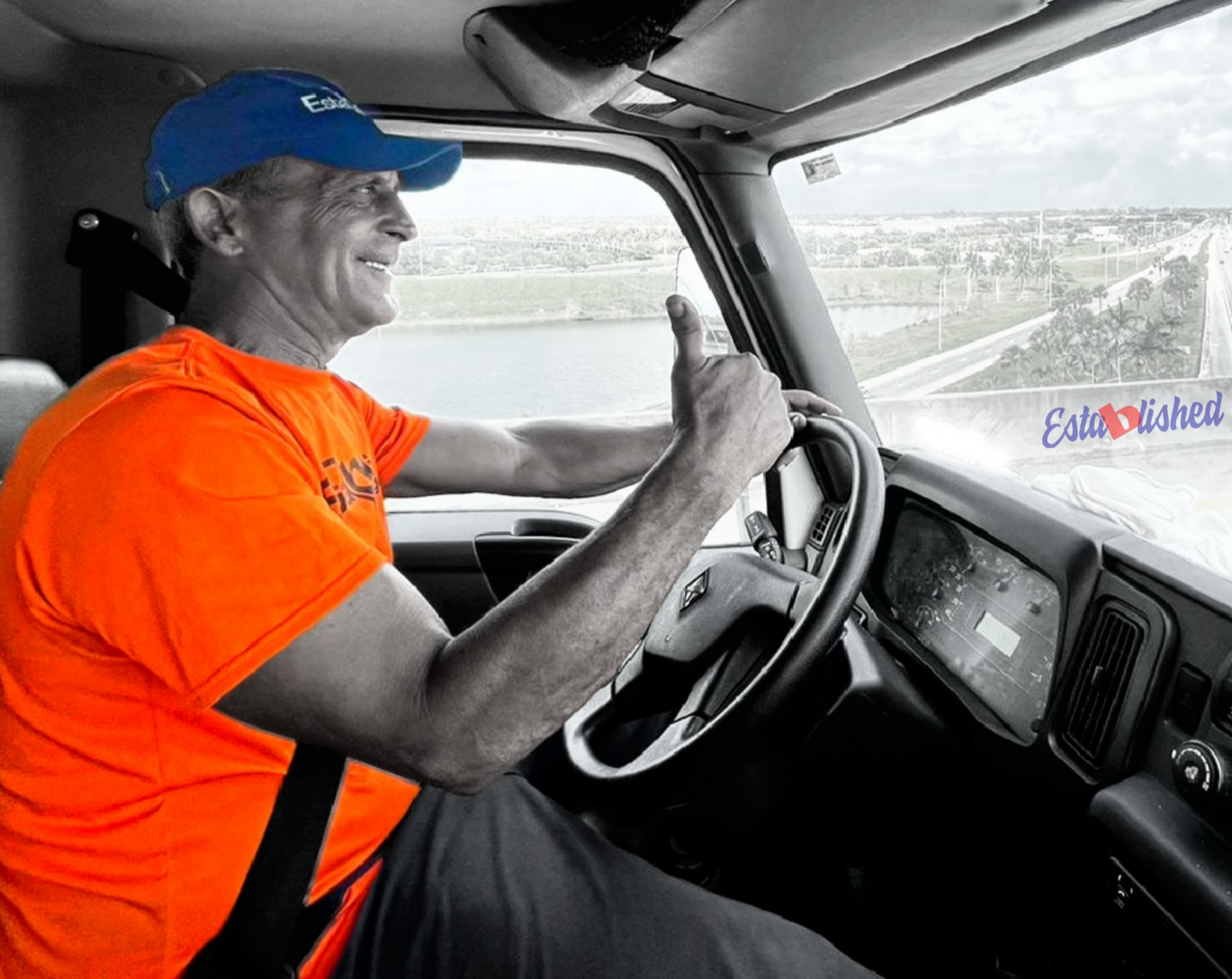 an established moving & storage truck driver gives a thumbs up on his way to a site