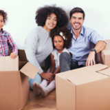 A family in their new home with a pile of moving boxes in front of them