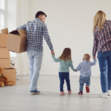 A family walking through an empty house with moving boxes